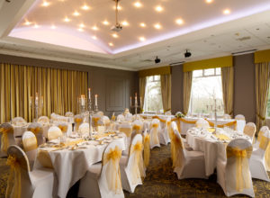 Tables and chairs dressed in yellow for a wedding in the Ballroom on the Park at Mercure Bradford Bankfield Hotel