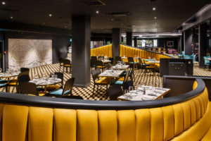 Newly refurbished Bar & Brasserie at Mercure Edinburgh City Princes Street Hotel with yellow bench seating and tables and chairs.