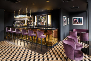 Newly refurbished Bar & Brasserie at Mercure Edinburgh City Princes Street Hotel with dark walls and purple plush bar stools.